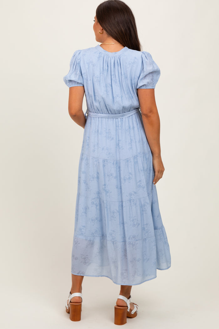 woman wearing a light blue maternity maxi dress with puff sleeves and a cinched waist, showing the back view