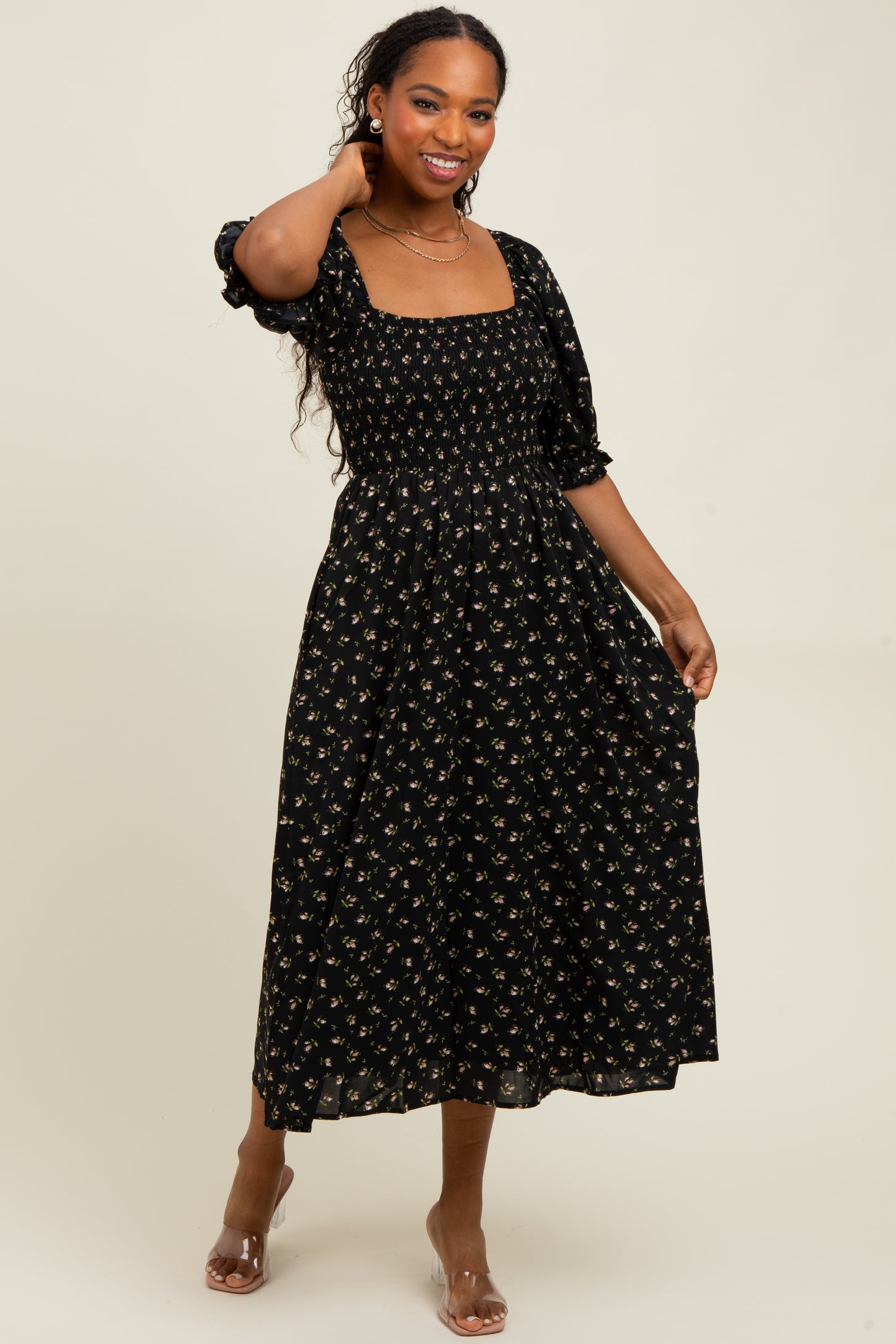 woman wearing a black floral midi dress with a square neckline and puff sleeves