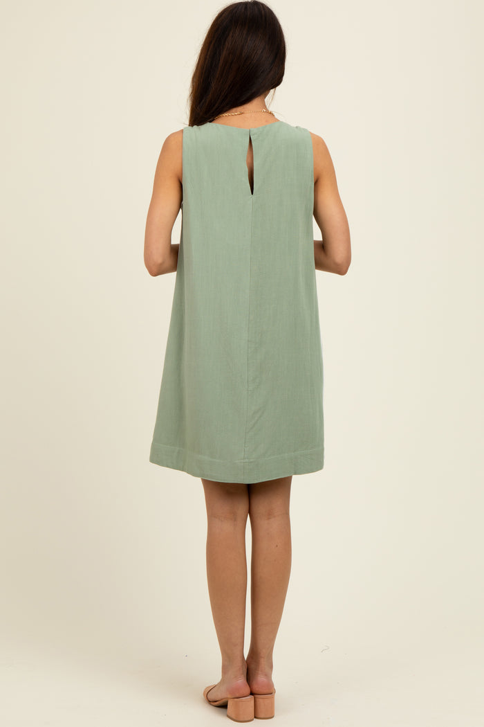 woman wearing a mint green sleeveless shift dress with a keyhole back detail