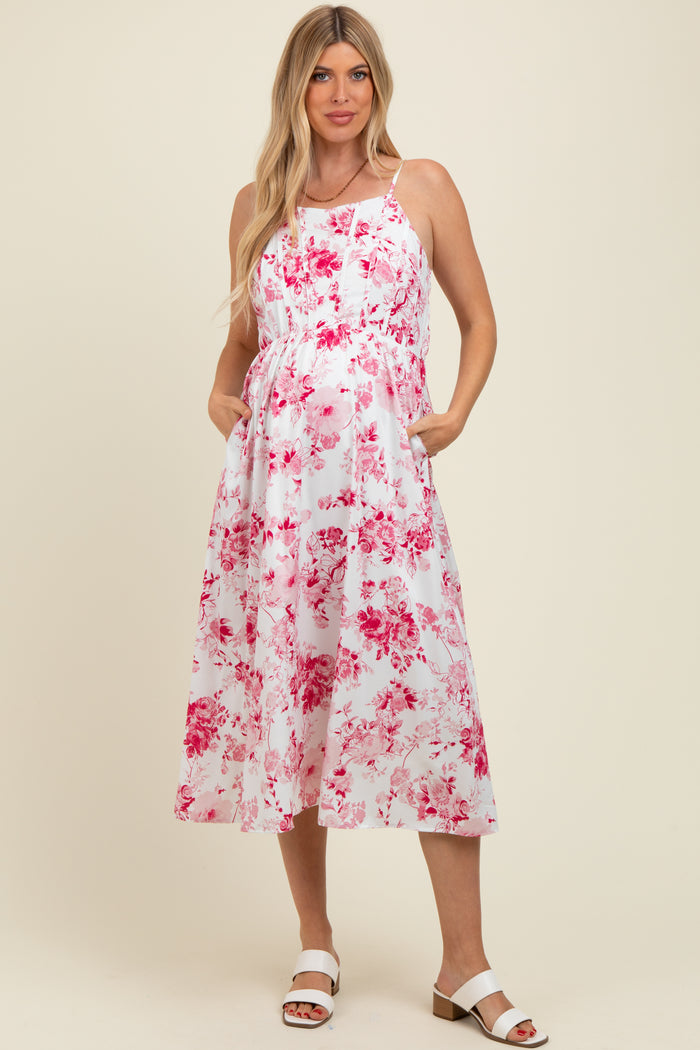woman wearing a floral pink and white maternity dress with pockets and a baby bump visible