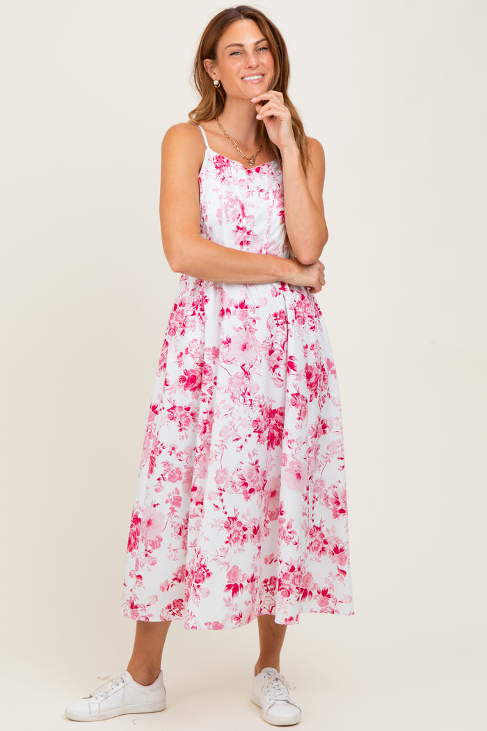 woman wearing a white floral midi dress with pink patterns and white sneakers