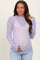 woman wearing a light purple maternity top with heart polka dots and a baby bump visible