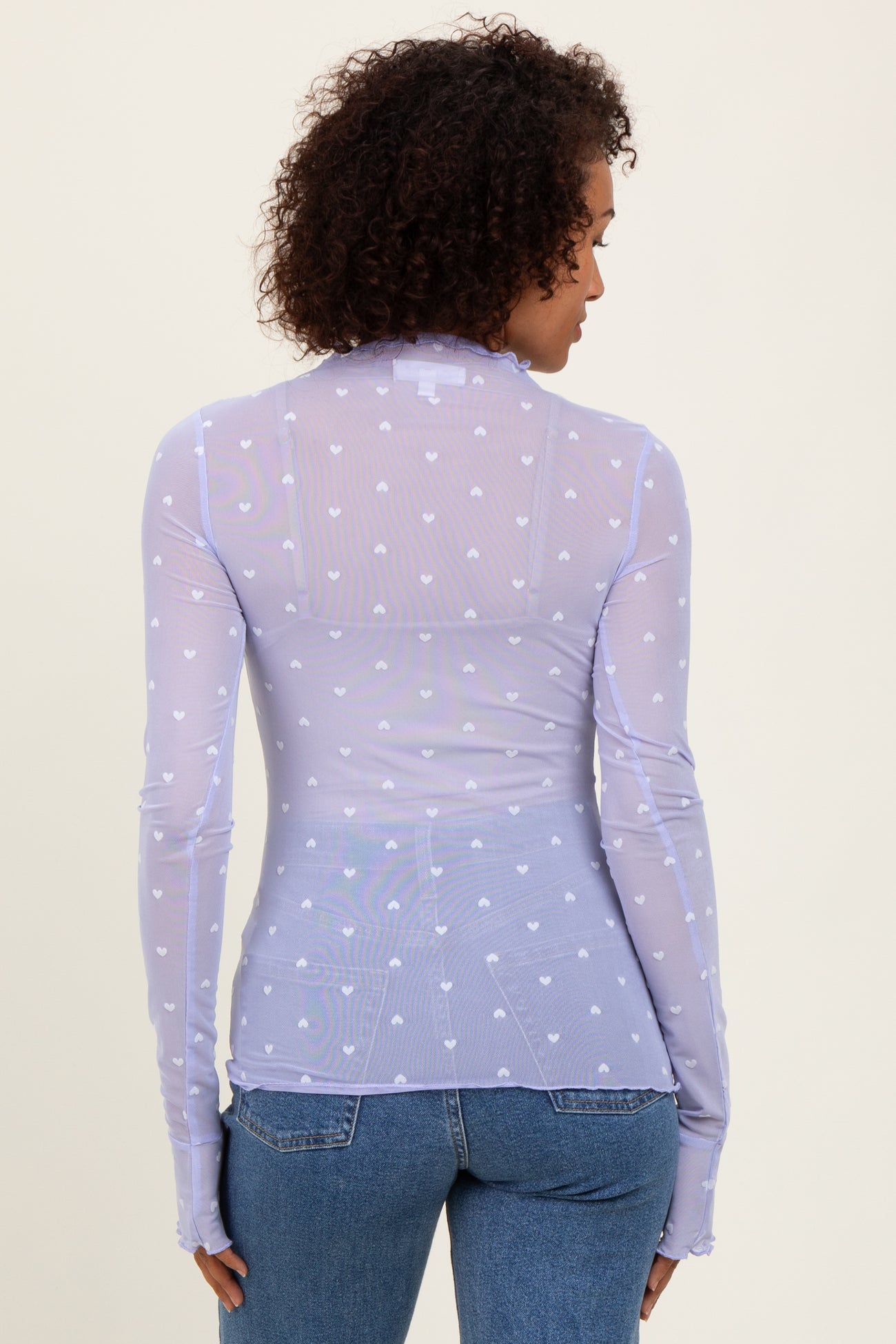 woman wearing a lilac long sleeve sheer top with heart patterns and fitted styling
