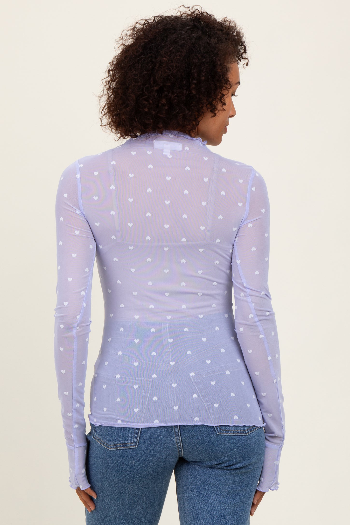 woman wearing a lilac long sleeve sheer top with heart patterns and fitted styling