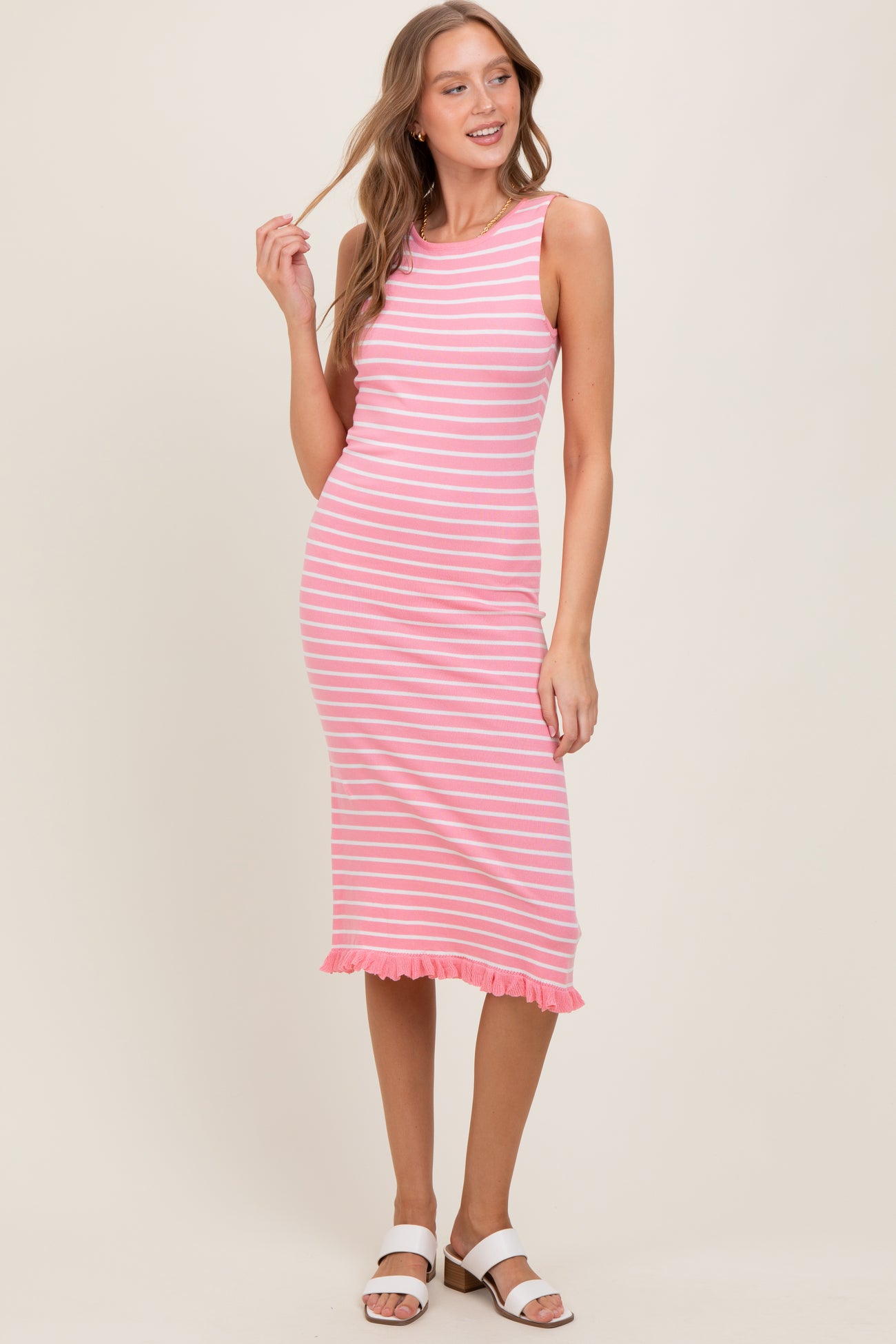 woman wearing a pink and white striped sleeveless midi dress with a ruffled hem and sandals