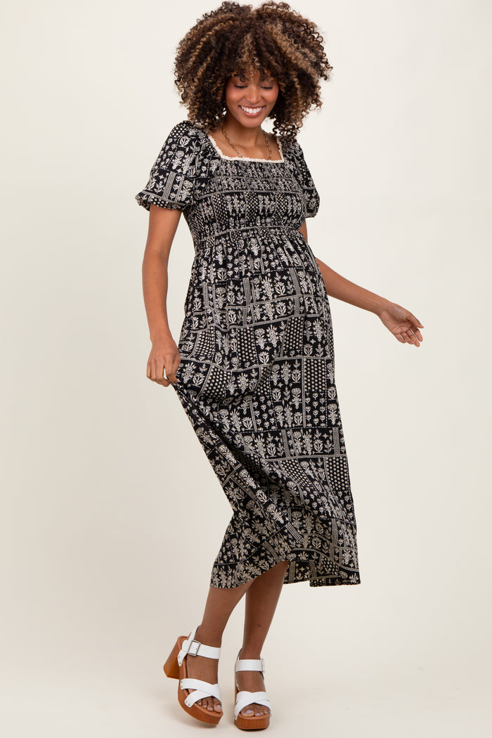 woman wearing a black and white patterned maternity dress with a square neckline and short puff sleeves, showing her baby bump