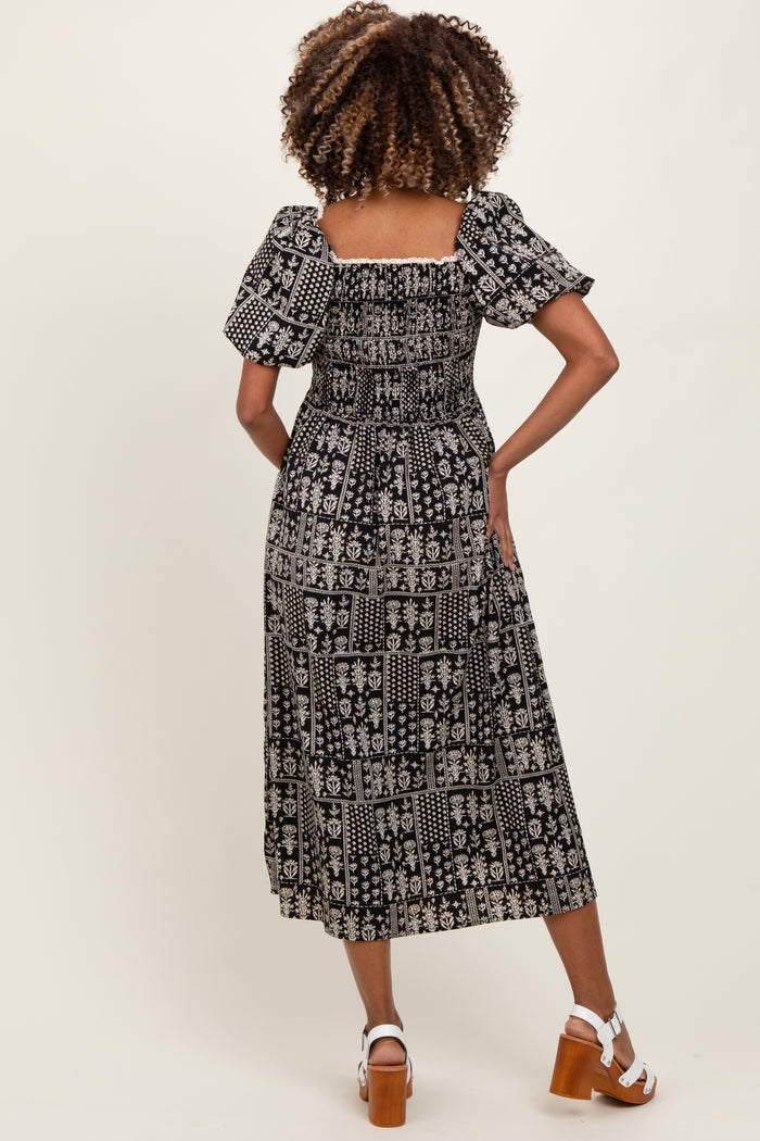 woman wearing a black and white patterned maternity maxi dress with puff sleeves, showing the back view
