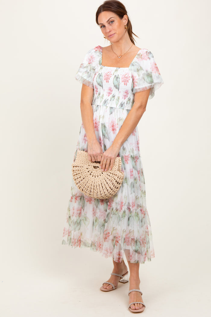 woman wearing a floral midi dress with puff sleeves and a square neckline, holding a woven clutch bag