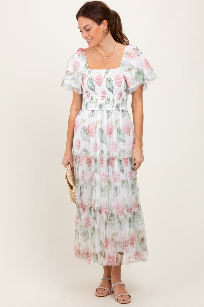 woman wearing a white floral maxi dress with puff sleeves and a square neckline, holding a clutch purse