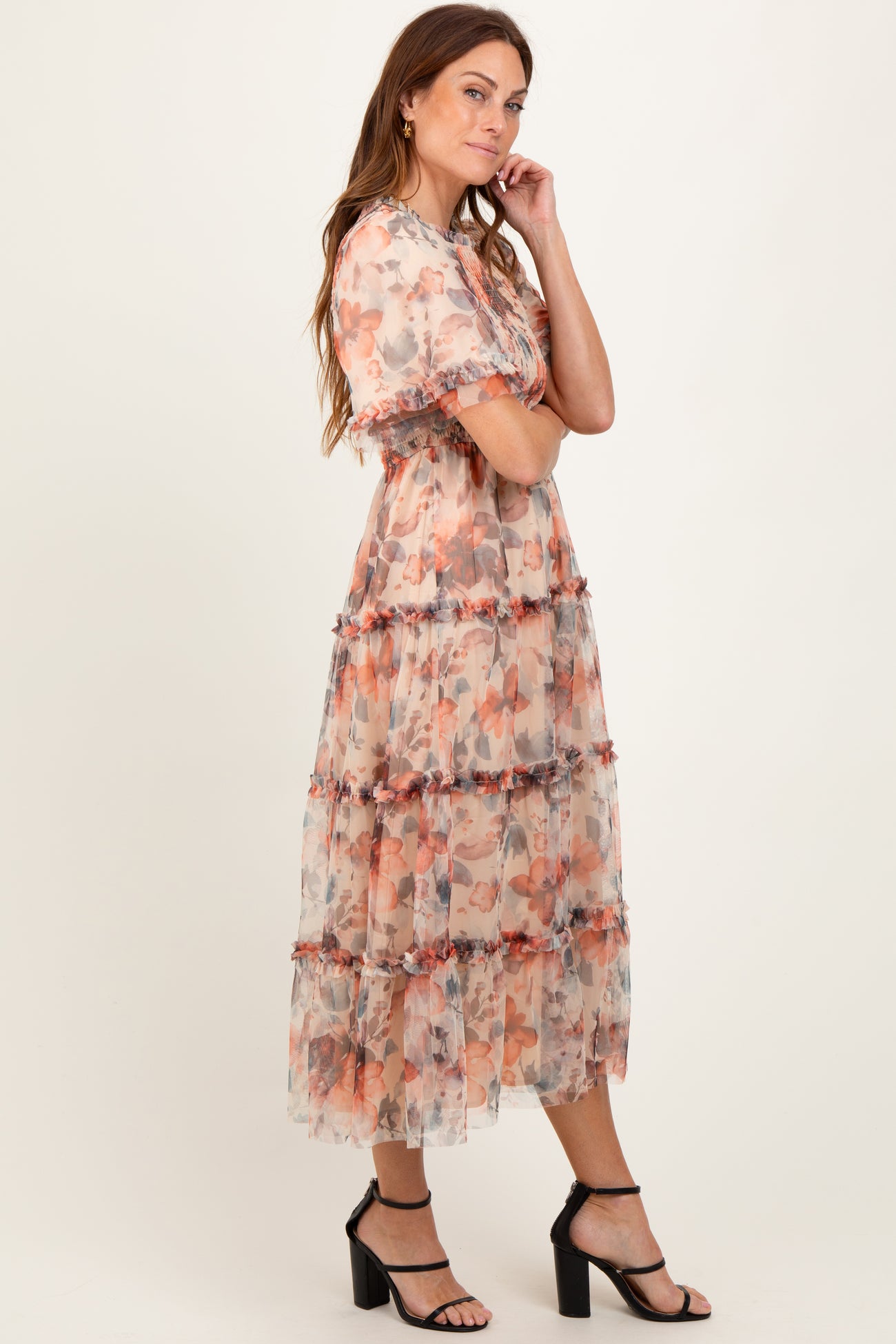 woman wearing a floral tiered maxi dress in soft colors with short sleeves and a flowy silhouette