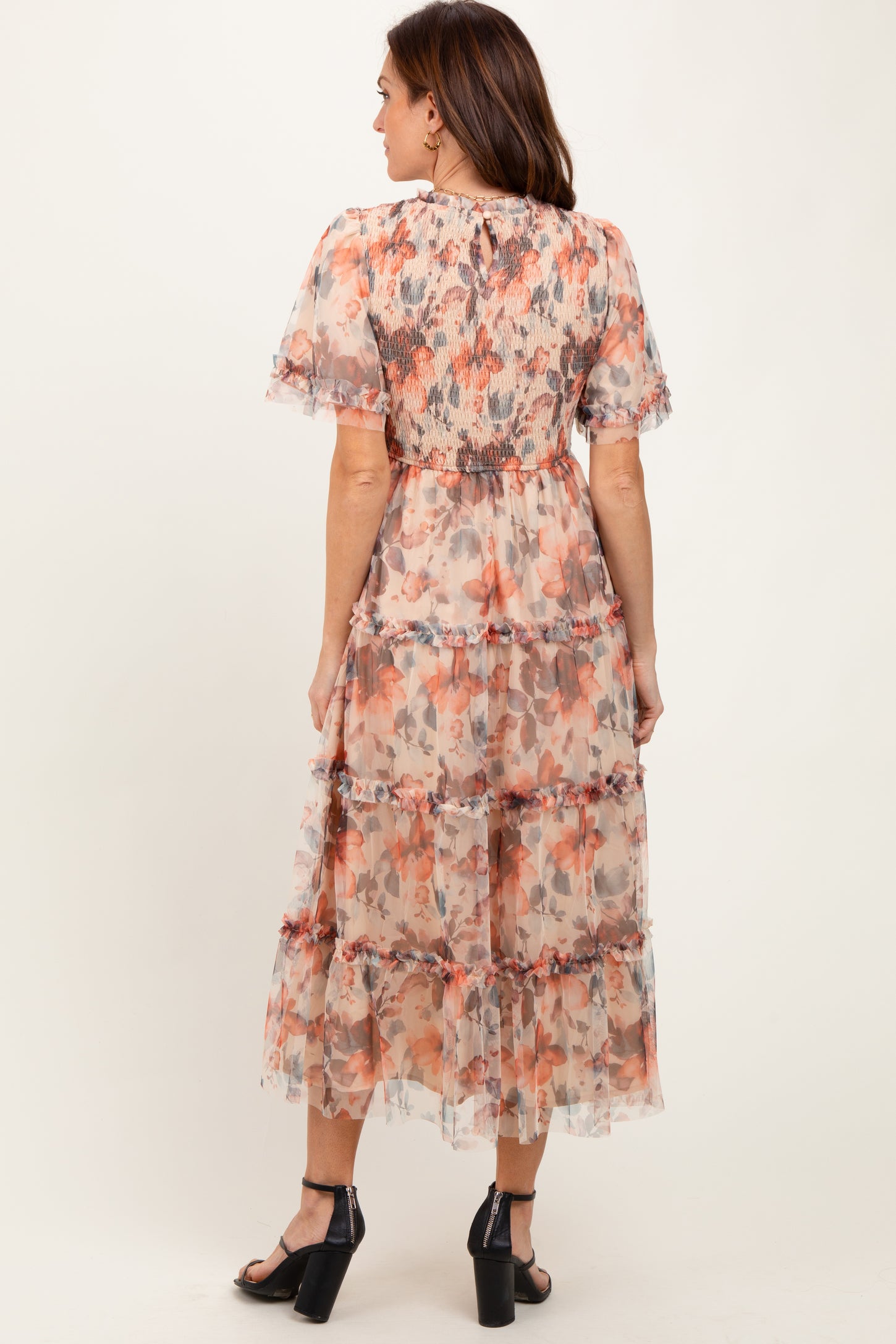 woman wearing a floral midi dress with tiered layers and puff sleeves, standing with her back to the camera