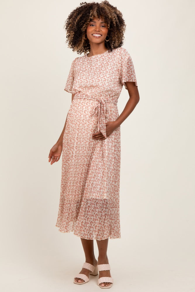 woman wearing a pink floral maternity dress with short sleeves and a tie waist, showing her baby bump