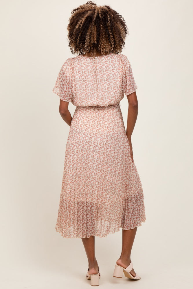 woman wearing a blush pink floral maternity dress with flutter sleeves and a tiered skirt, showing her baby bump from the back