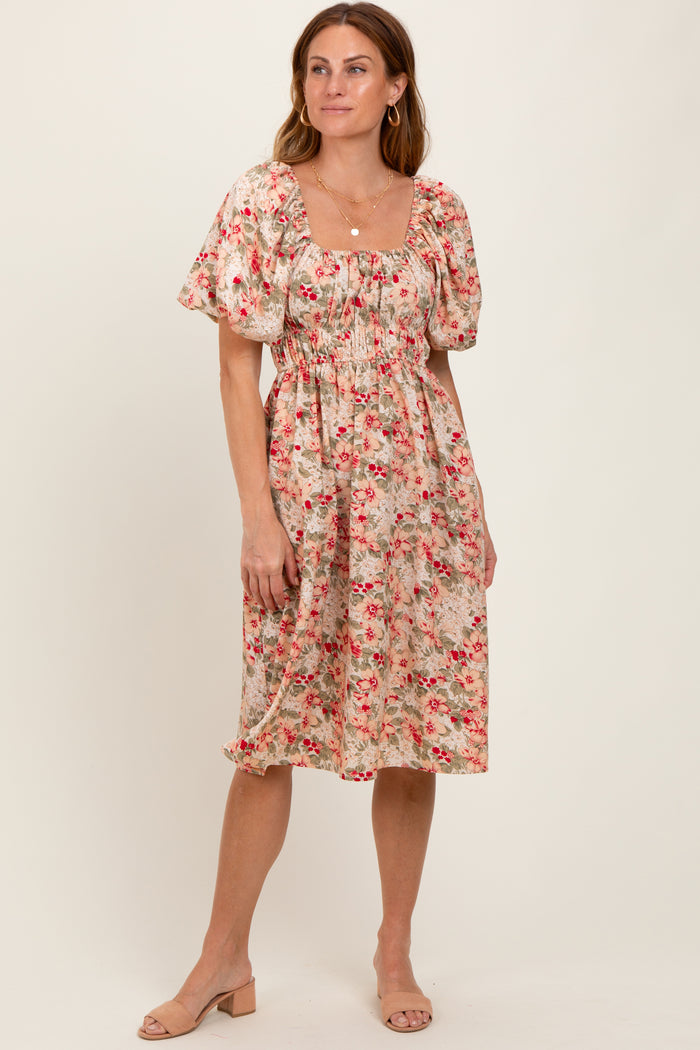 woman wearing a floral midi dress with puff sleeves and a cinched waist, standing on a neutral background