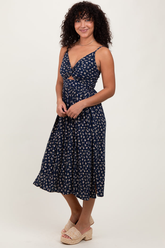 woman wearing a navy floral midi dress with a sweet heart neckline and braided straps, standing and smiling