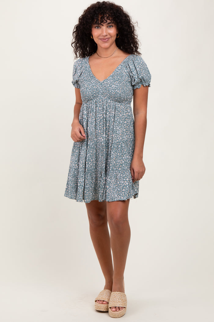 woman wearing a blue floral short dress with short puff sleeves and a v-neckline, standing pose