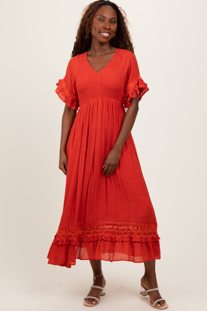 woman wearing a red midi dress with ruffled sleeves and lace detailing at the hem