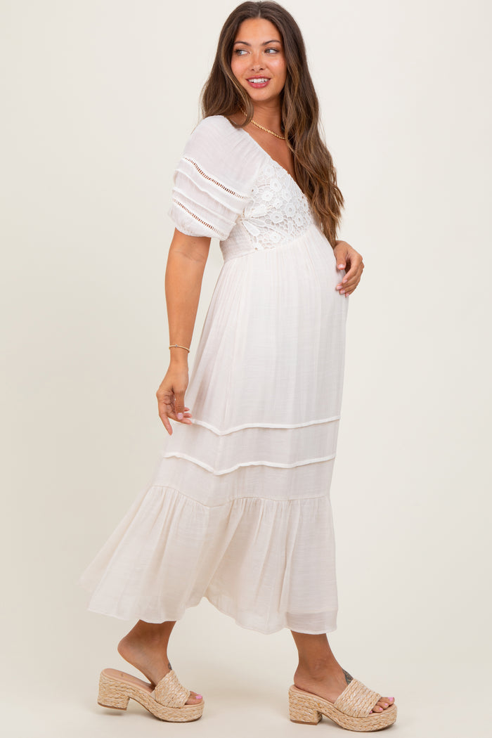 woman wearing a white maternity dress with puff sleeves and lace details, showing off her baby bump