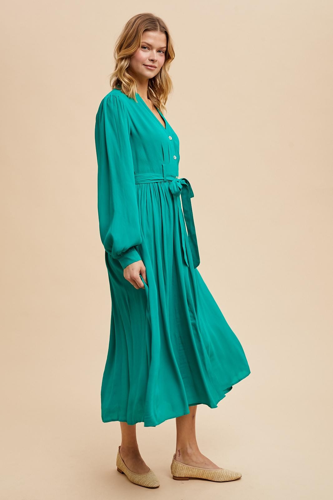 woman wearing a teal long sleeve button-down midi dress with a tie belt and stylish flat shoes