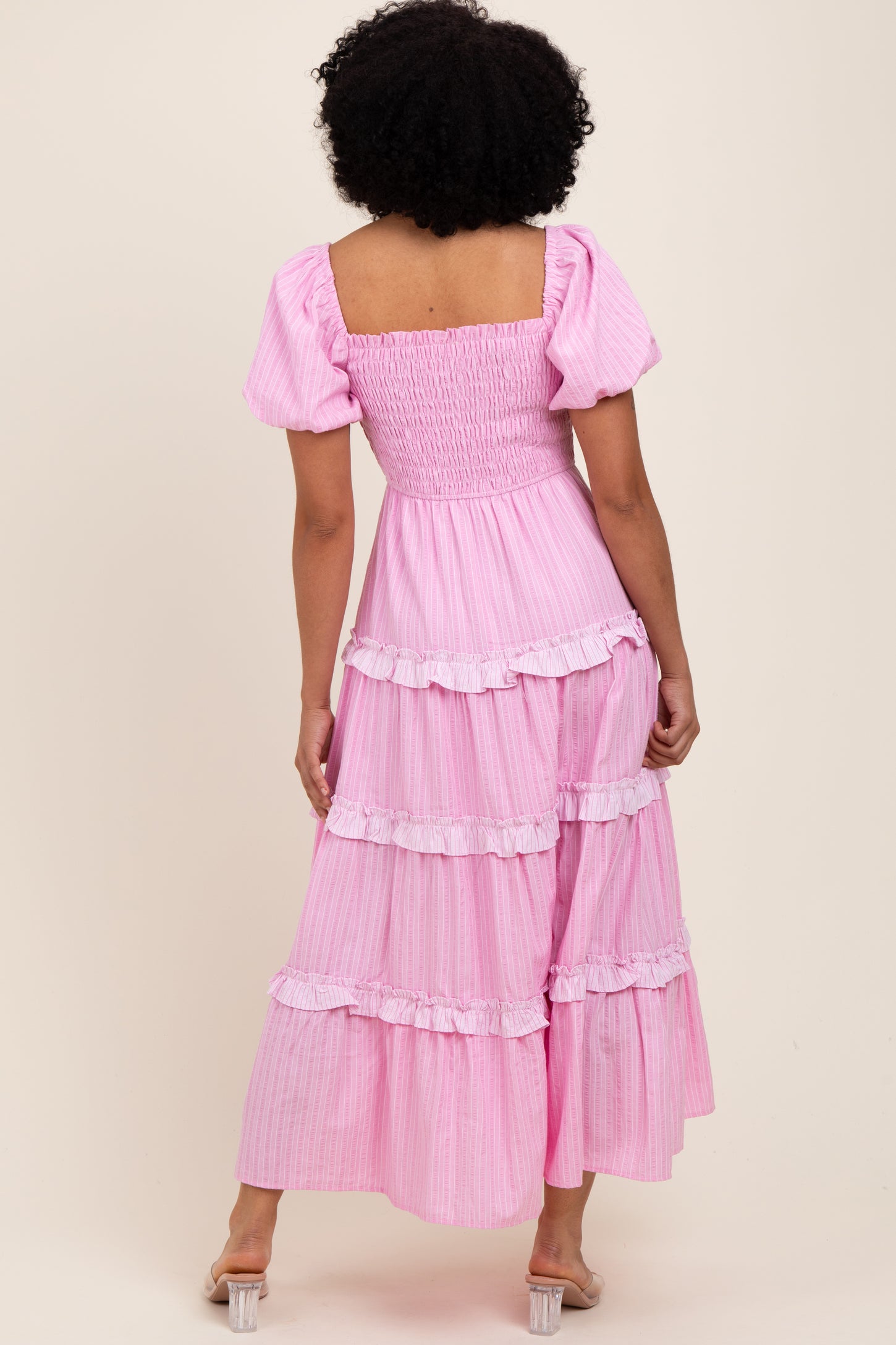 woman wearing a pink tiered maxi dress with puff sleeves and a smocked bodice, showing the back view