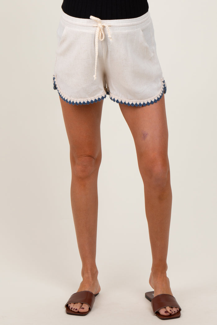 woman wearing white maternity shorts with blue scalloped detailing and drawstring waist