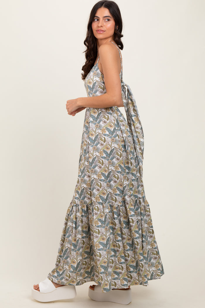 woman wearing a floral print maxi dress with a tie-back detail and a tiered skirt, standing sideways