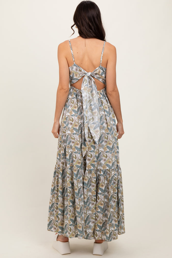 woman wearing a backless floral maxi dress with a tied bow detail and a tiered skirt