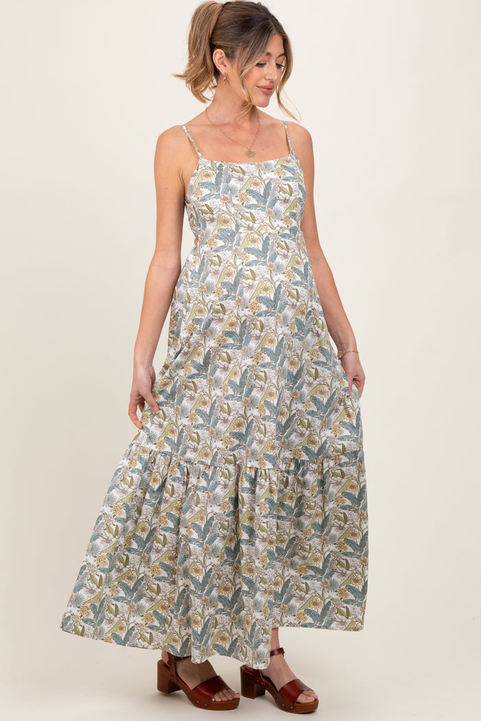 woman wearing a patterned maxi maternity dress with thin straps and a tiered skirt, showing her baby bump