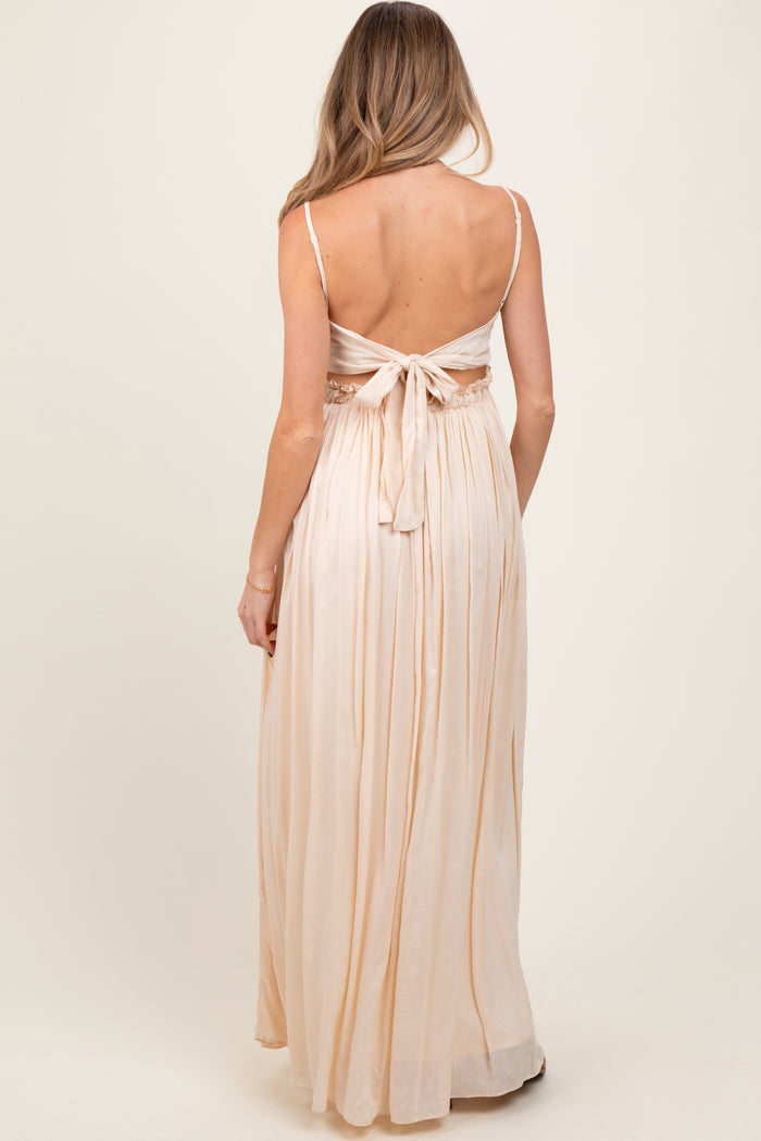 woman wearing a light peach maternity maxi dress with a tie back and flowing skirt, seen from the back