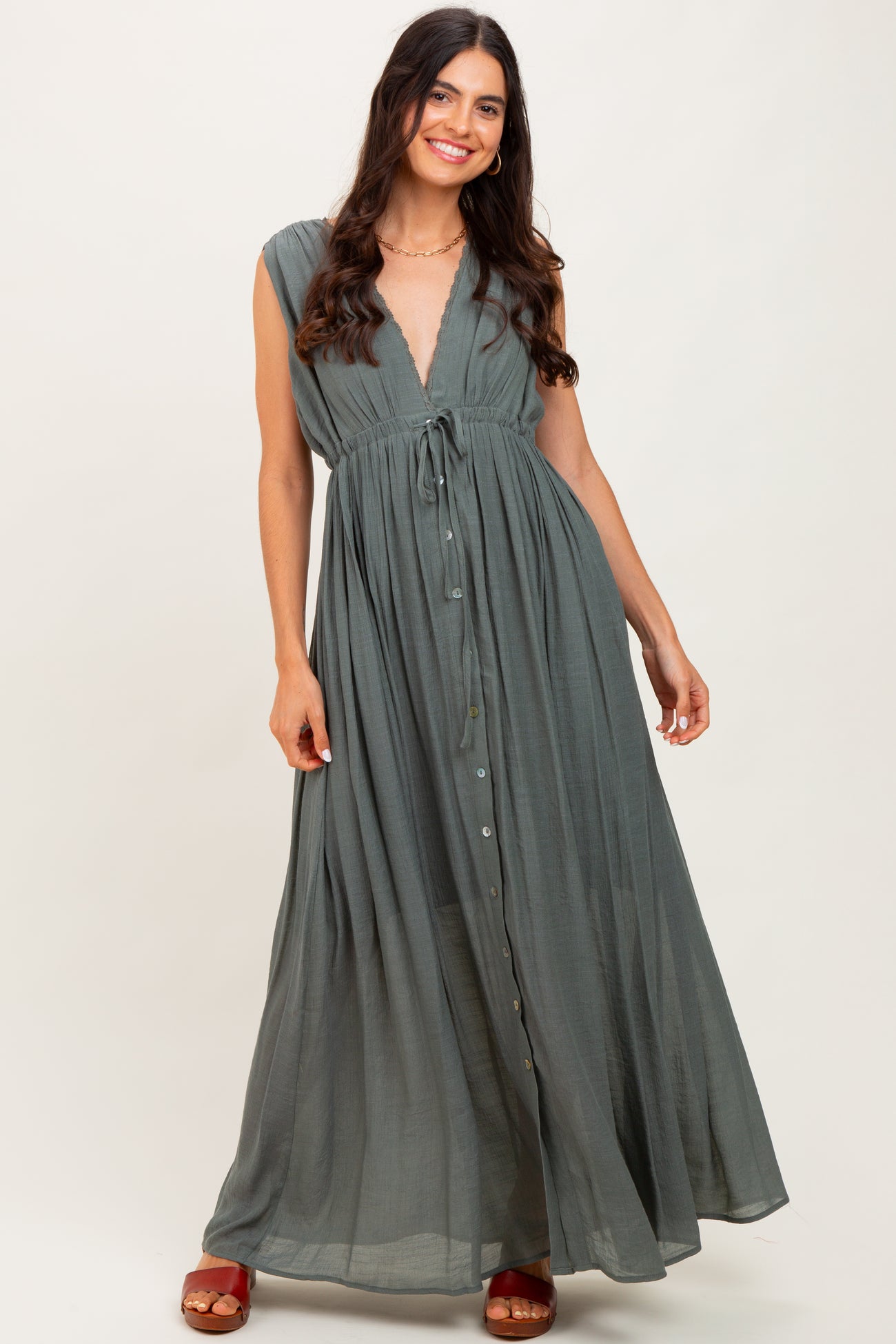woman wearing a long olive green maxi dress with a deep v-neck and tie waist detail