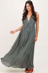 woman wearing a flowy olive green maxi dress with a deep v-neck and button details, standing gracefully