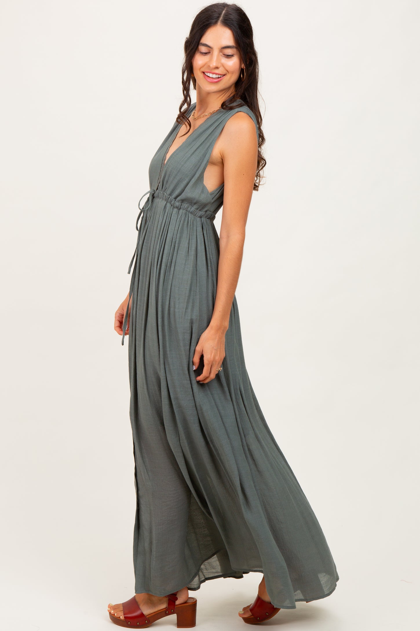 woman wearing a green sleeveless maxi dress with a tied waist and side slits