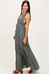 woman wearing a green sleeveless maxi dress with a tied waist and side slits