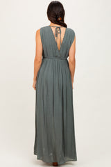 woman wearing a dusty green backless maxi dress with a tied detail at the neck and a flowy skirt