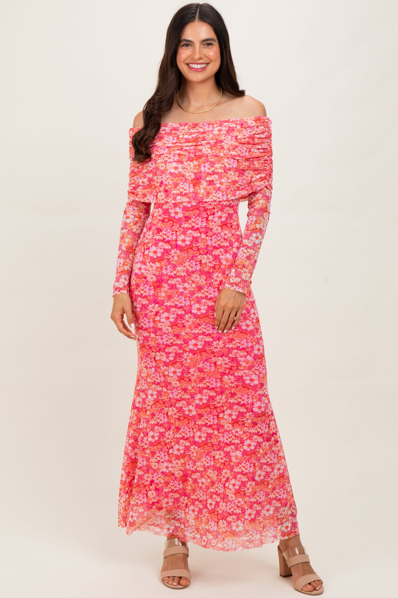 woman wearing a pink floral off-the-shoulder maxi dress with long sleeves and a fitted silhouette