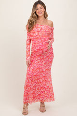 woman wearing a pink off-shoulder floral maternity dress and holding her baby bump