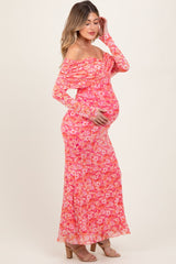 woman wearing a pink floral off-the-shoulder maternity dress and holding her baby bump