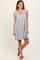 woman wearing a gray striped sleeveless swing dress and brown sandals, standing against a neutral background