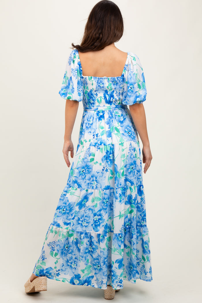 woman wearing a blue and white floral maxi dress with puff sleeves and a square neckline, back view