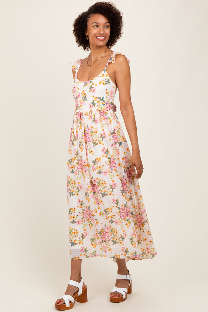 woman wearing a white floral maxi dress with ruffled straps and a fitted bodice