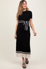 woman wearing a black ribbed maternity dress with a tied waist and cream striped hem, showcasing her baby bump