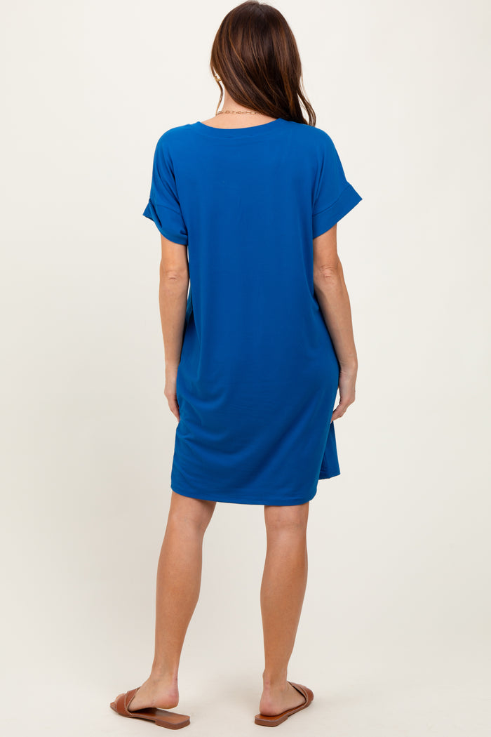 woman wearing a blue short sleeve tunic dress, standing with her back to the camera