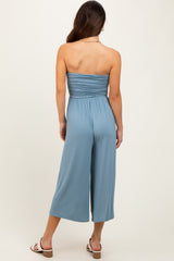 woman wearing a back view of a light blue strapless jumpsuit with a fitted bodice and wide-leg pants