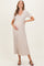 woman wearing a beige ribbed maternity dress with a v-neck and short sleeves, holding her baby bump