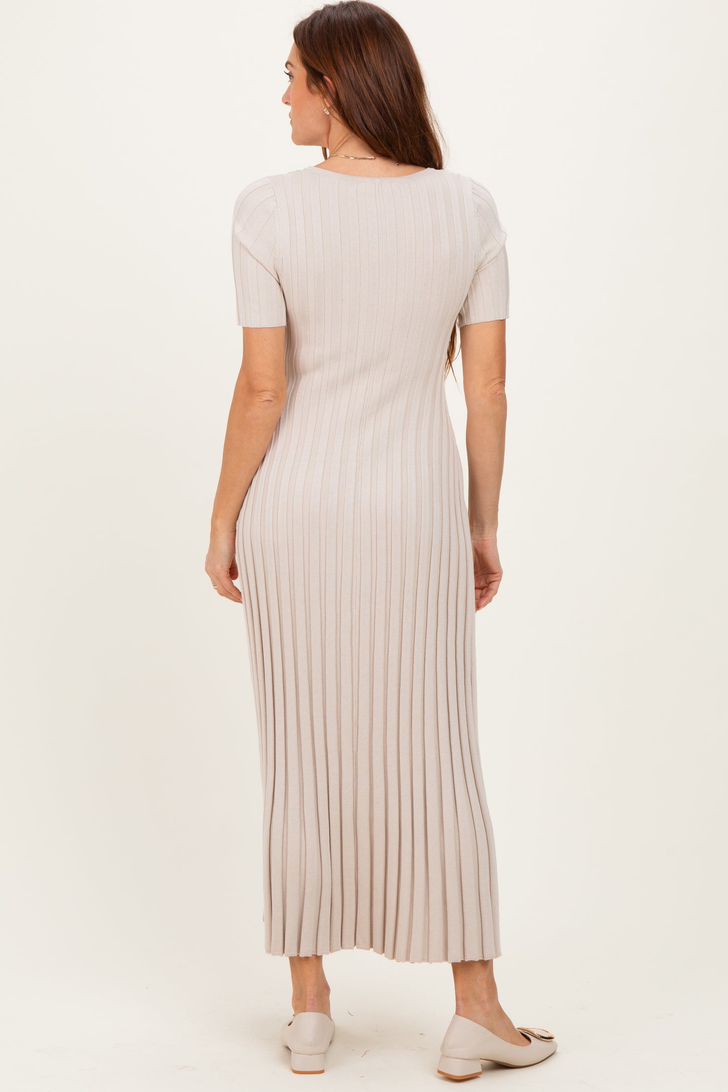 woman wearing a light beige ribbed midi dress with short sleeves and a fitted silhouette, viewed from the back