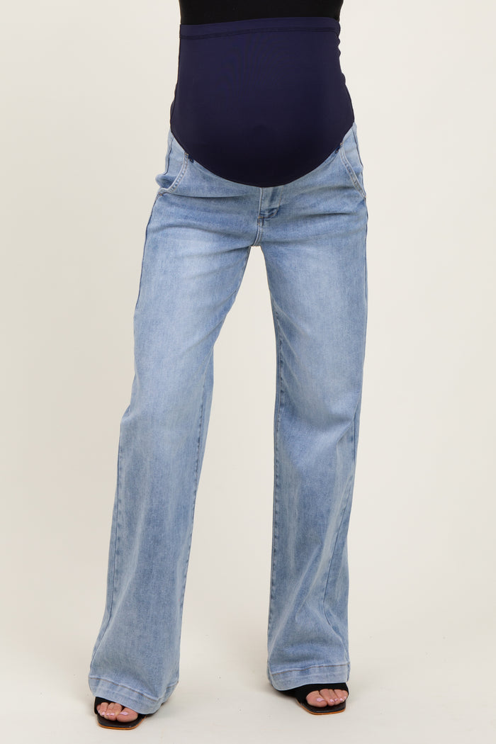 woman wearing light wash maternity jeans with a dark blue over-the-bump waistband