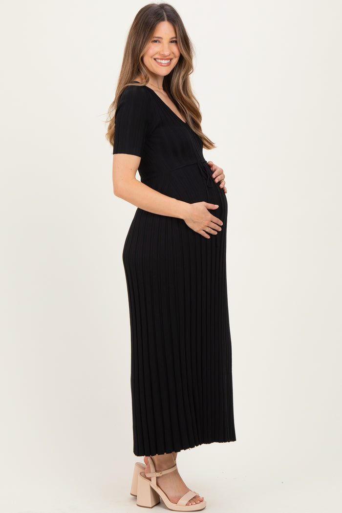 woman wearing a black ribbed maternity maxi dress and holding her baby bump