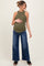 woman wearing a dark green ribbed maternity tank top and wide leg jeans, holding her baby bump