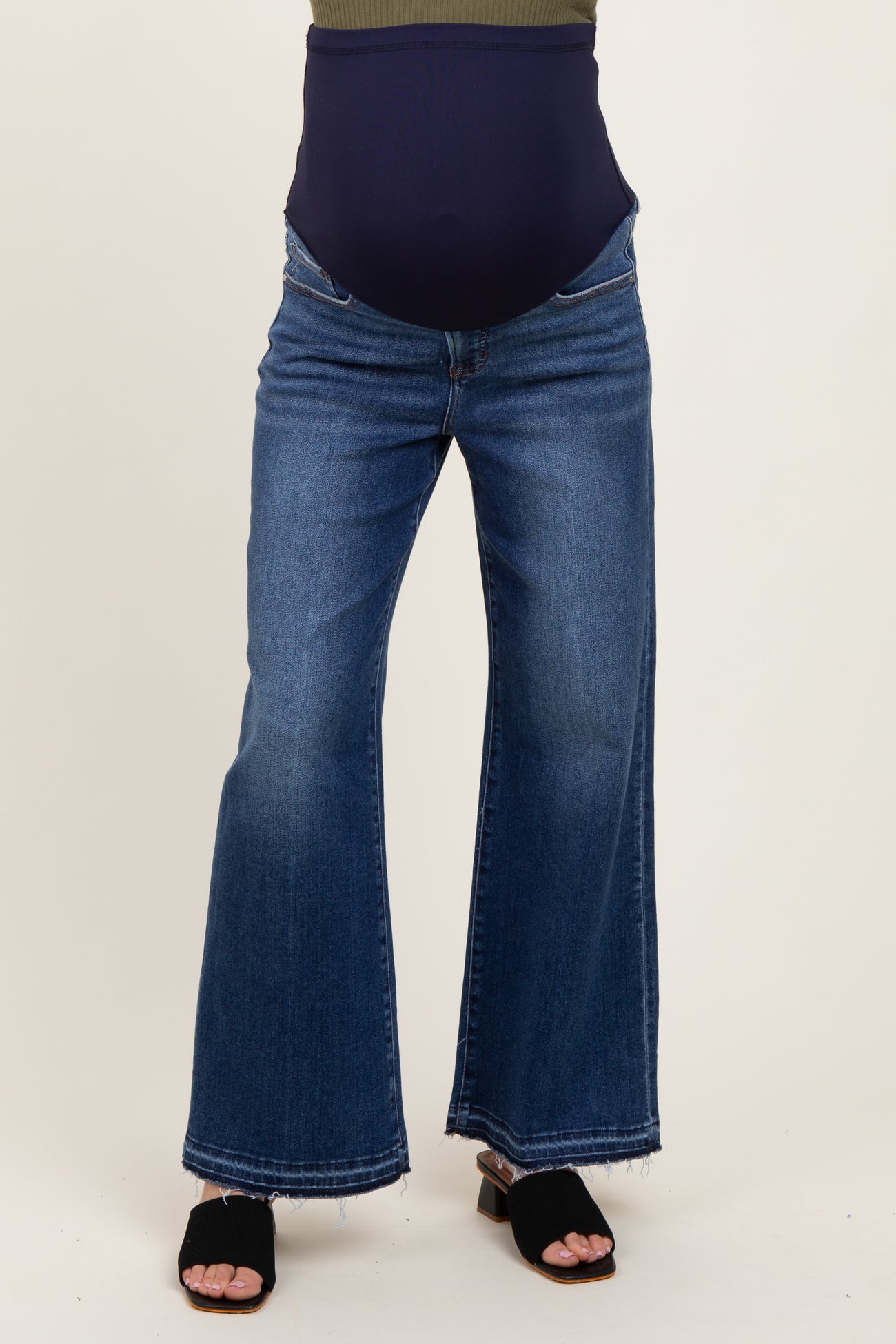 maternity wear blue flared jeans with a over-the-bump waistband, model wearing black sandals and a dark top