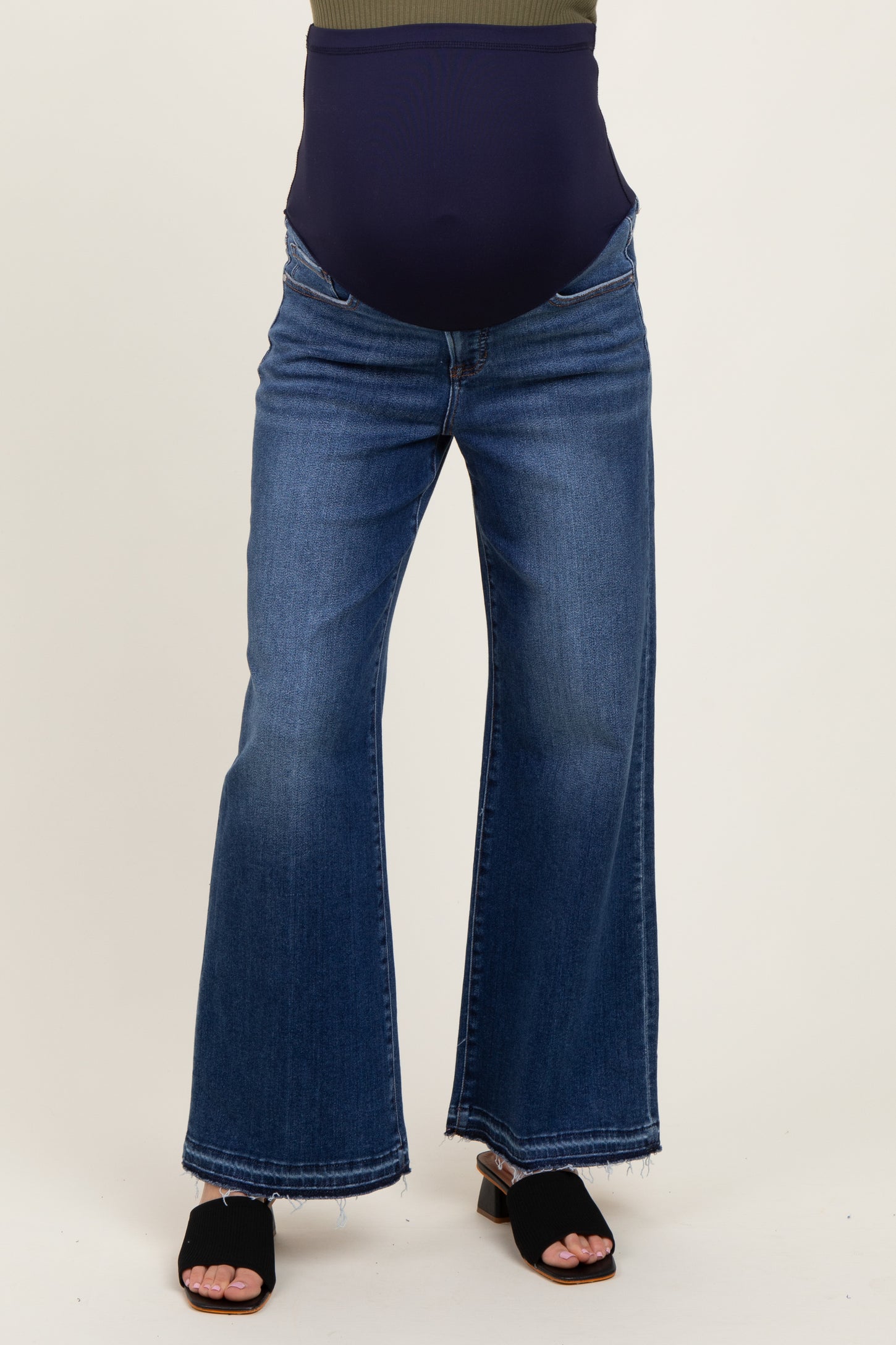 maternity wear blue flared jeans with a over-the-bump waistband, model wearing black sandals and a dark top